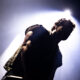 Low-angle shot of a performer on stage, backlit by a bright light, with a watermark in the bottom-right corner.