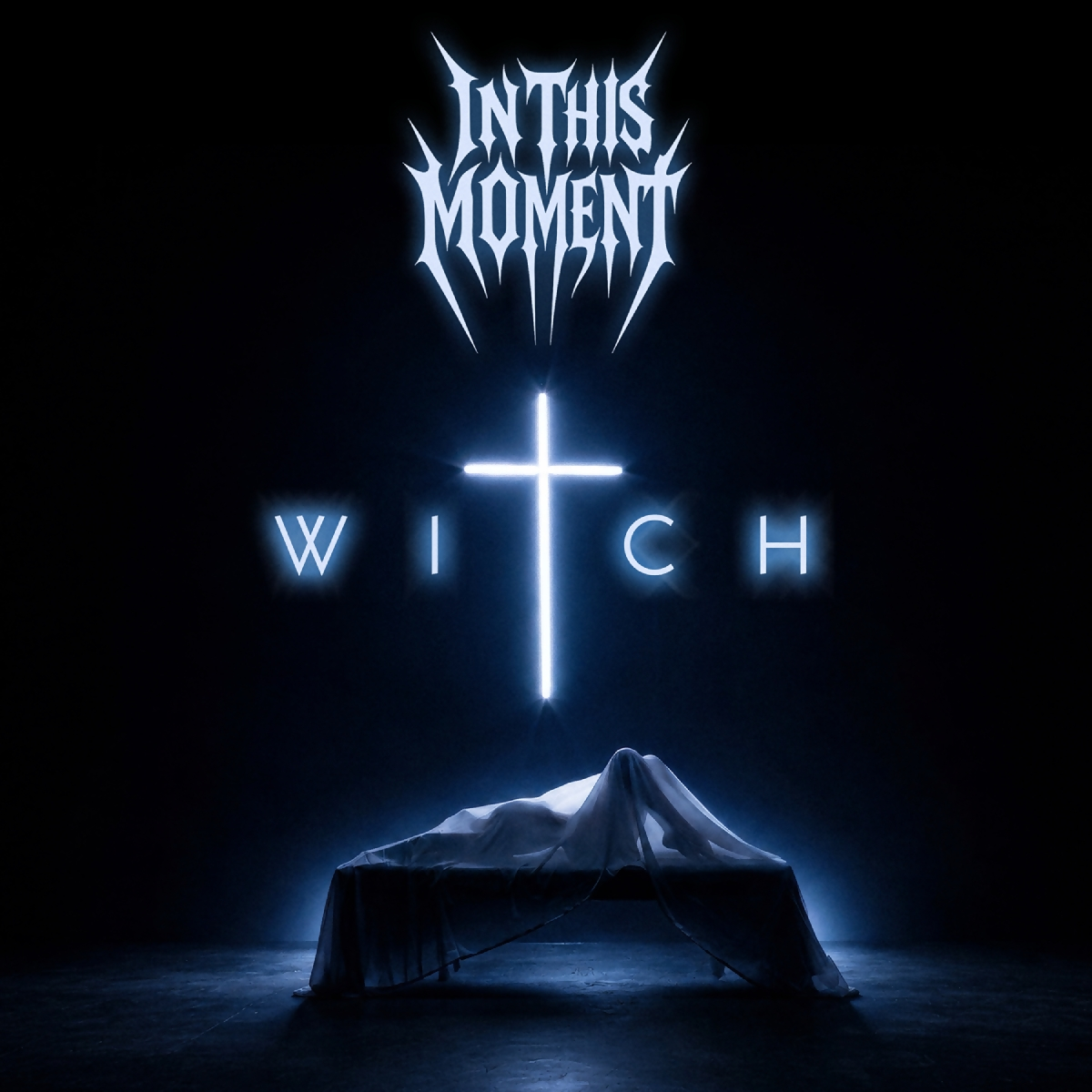 image - Strife Mag Album cover: In This Moment logo above a glowing cross with the word WITCH and a draped figure beneath a cloth on a table.